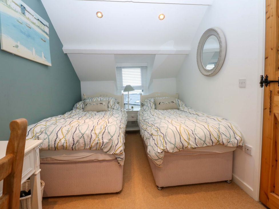 A bedroom with two single beds and a bedside table at Bryn Mor Cottage in Mynytho near Llanbedrog