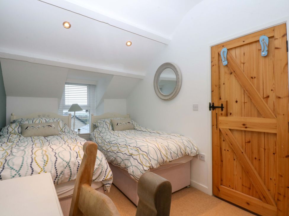 A bedroom with two beds and a door at Bryn Mor Cottage in Mynytho near Llanbedrog