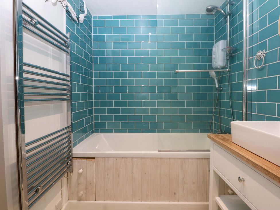 A bathroom with a bathtub and shower at Bryn Mor Cottage in Mynytho near Llanbedrog
