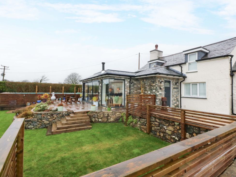 A garden area with a house and a glass extension at Bryn Mor Cottage in Mynytho near Llanbedrog