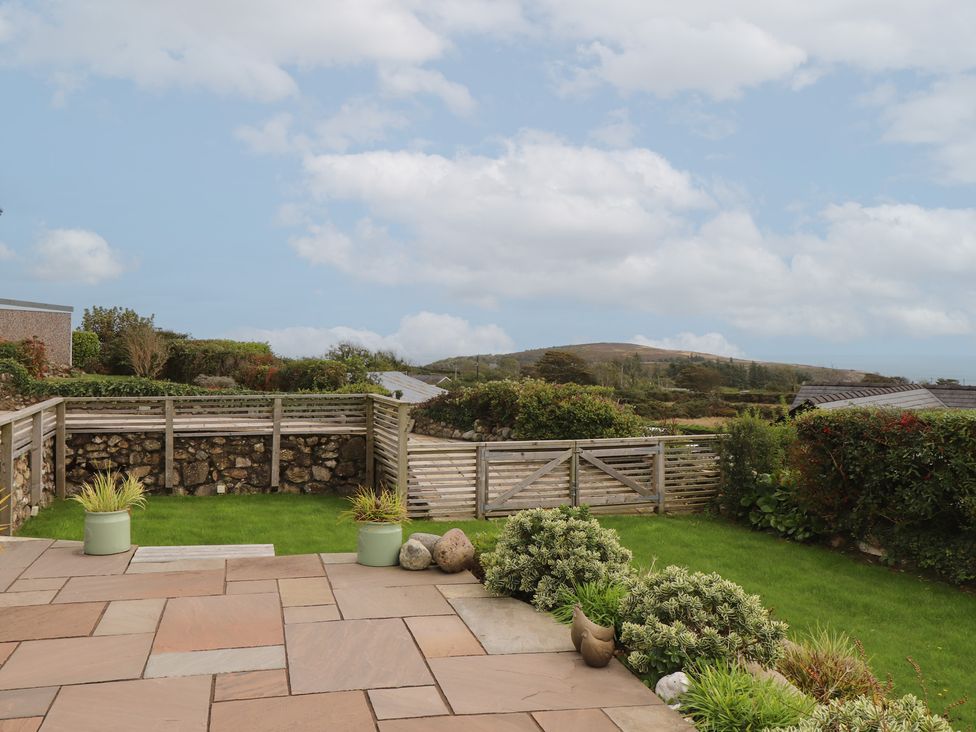 A garden with a patio and greenery at Bryn Mor Cottage near Llanbedrog