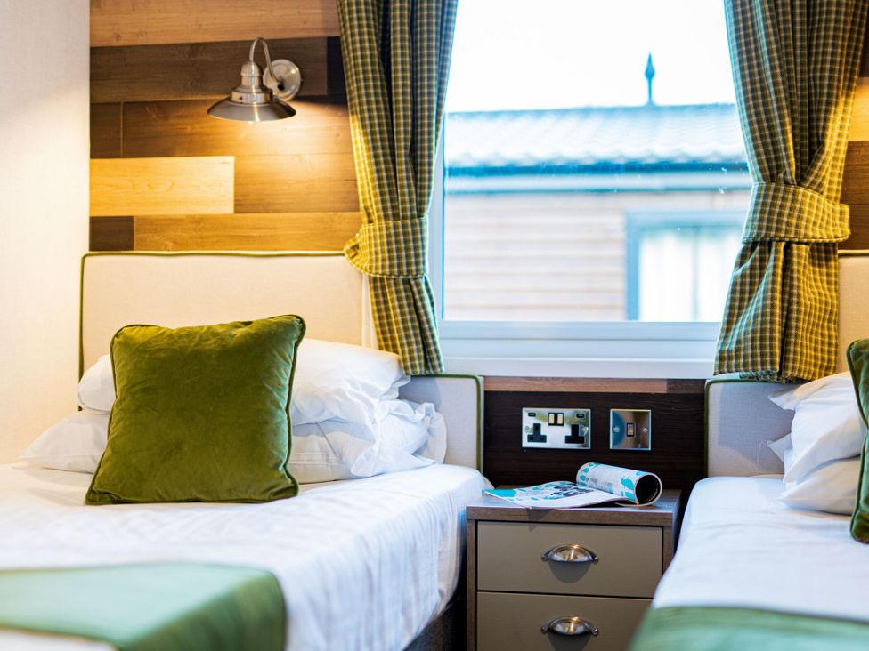 A bedroom with two beds and a nightstand at Brayford Lodge Spa in Louth