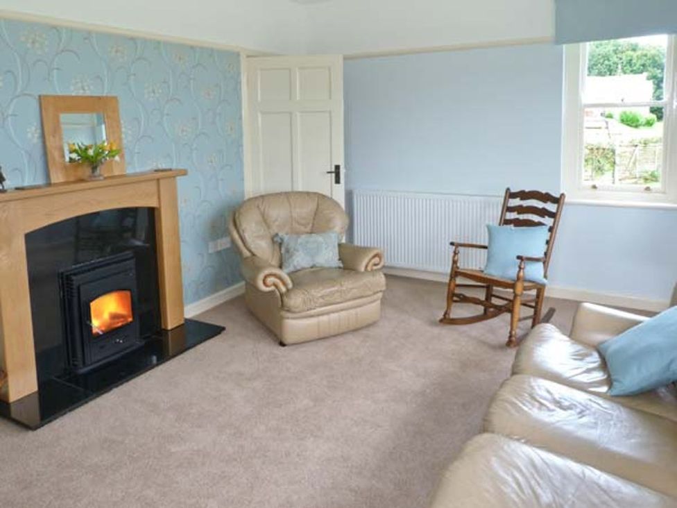 A living room with a fireplace and a rocking chair at Priory View in Ulverston