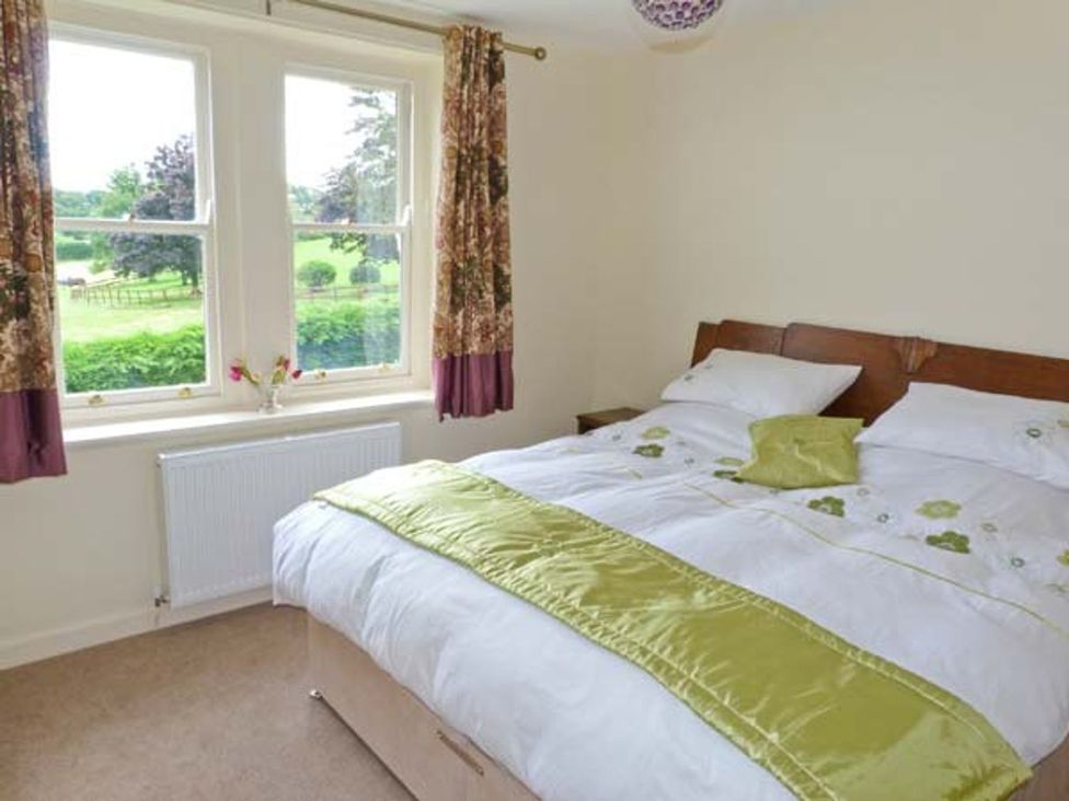 A bedroom with a bed and windows at Priory View Ulverston