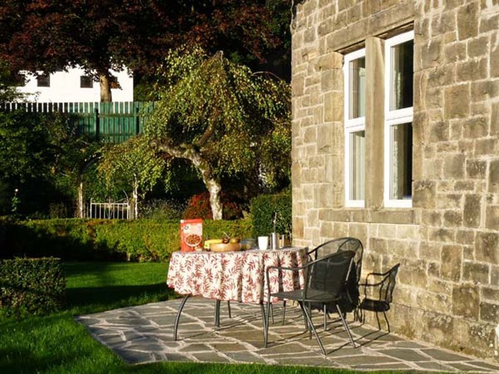A garden with a table and chairs by the stone wall at Priory View in Ulverston