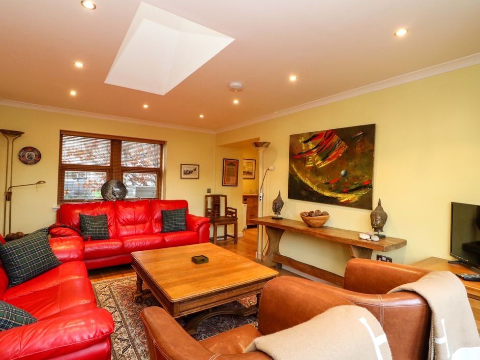 A living room with red sofas and a coffee table at 78 Findhorn in Forres