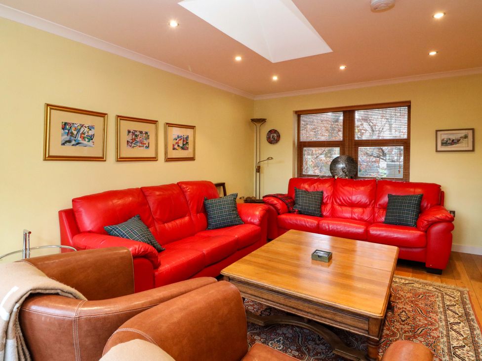 A living room with a red sofa and wooden coffee table at 78 Findhorn in Forres