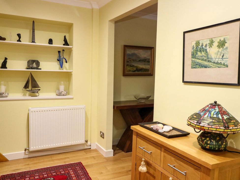 A hallway with sculptures on shelf and a lamp on a chest of drawers at 78 Findhorn in Forres