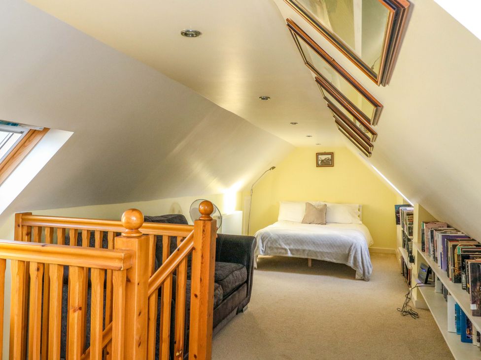 A loft with a bed, sofa, and bookshelves at 78 Findhorn in Forres