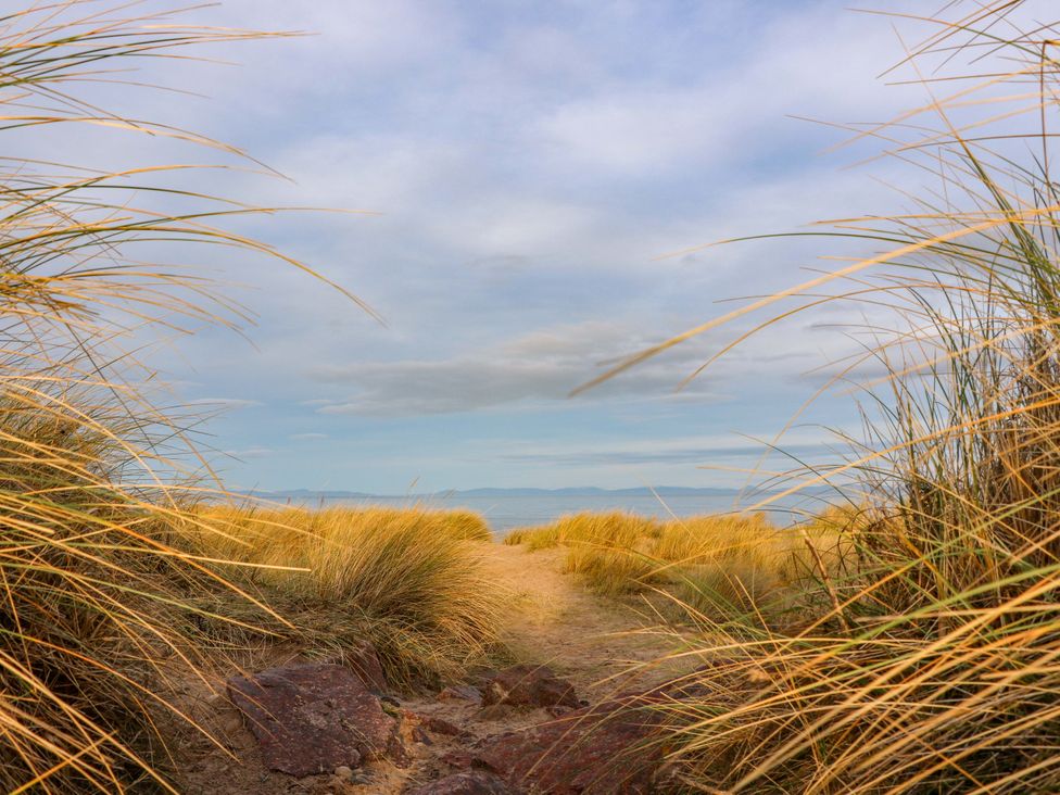 A sandy path bordered by grasses leading to the ocean at 78 Findhorn in Forres