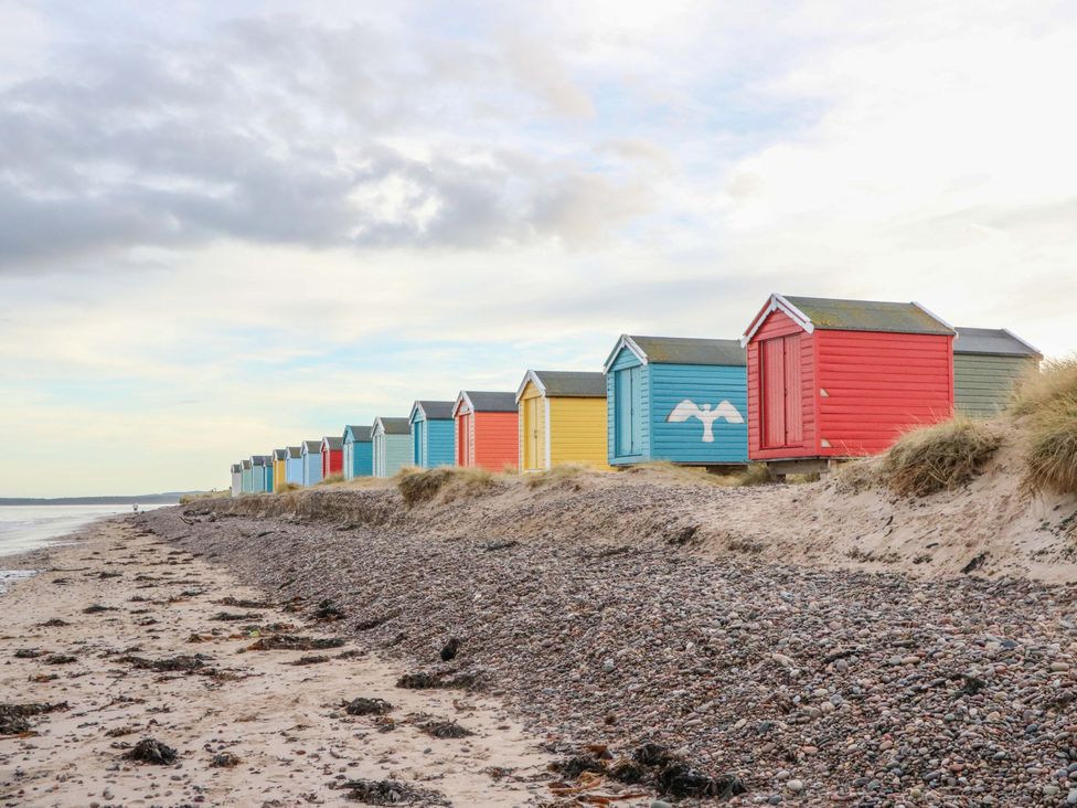 Beach huts lined along a beach at 78 Findhorn in Forres