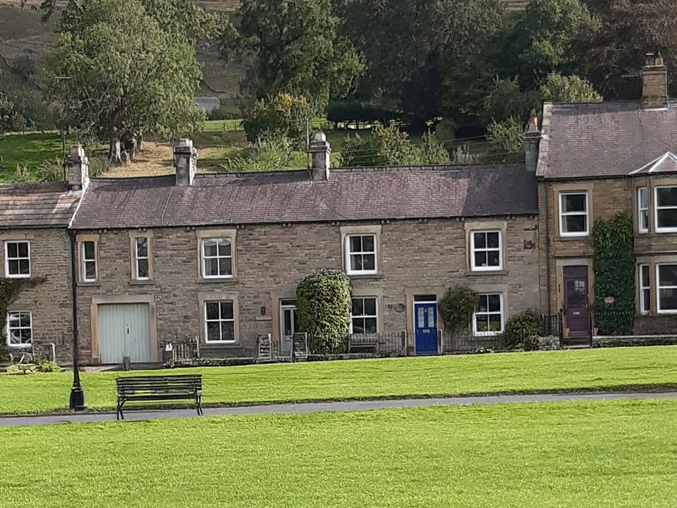 A row of houses with a bench and grass at Ivy Cottage in West Burton