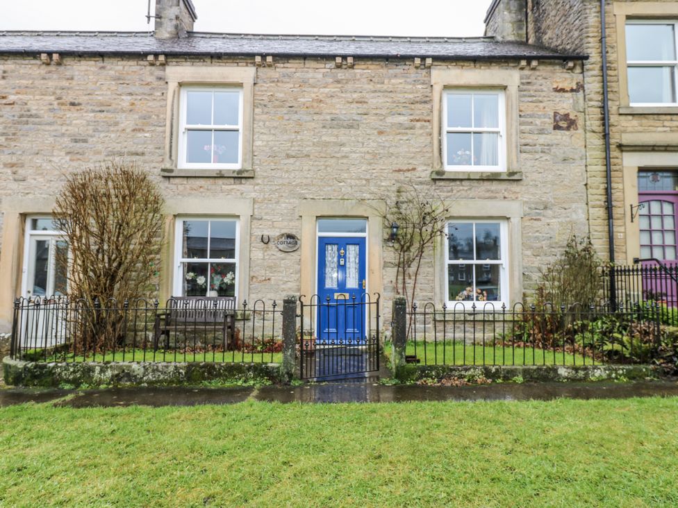 A house with a blue door and windows at Ivy Cottage in West Burton