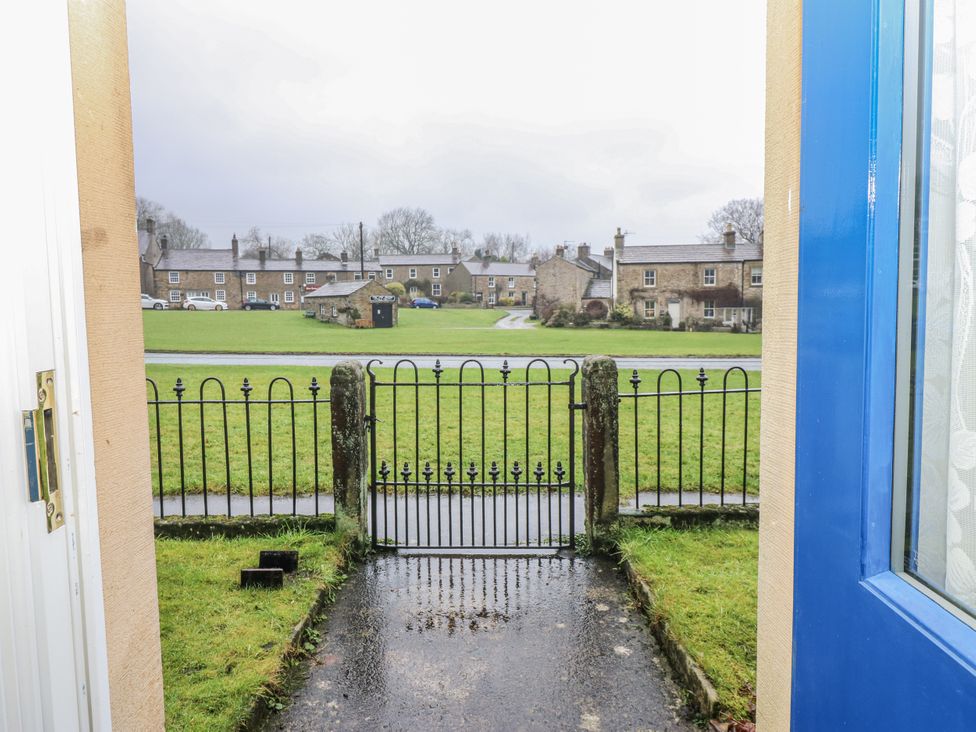 A view of a gate and houses from the doorway at Ivy Cottage in West Burton