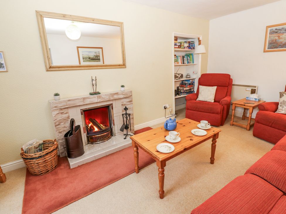 A living room with a fireplace and seating at Ivy Cottage in West Burton