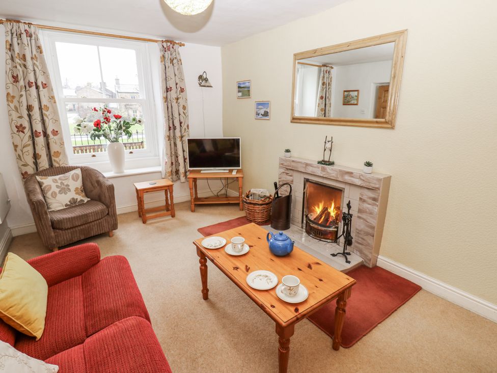A living room with a fireplace and television at Ivy Cottage in West Burton