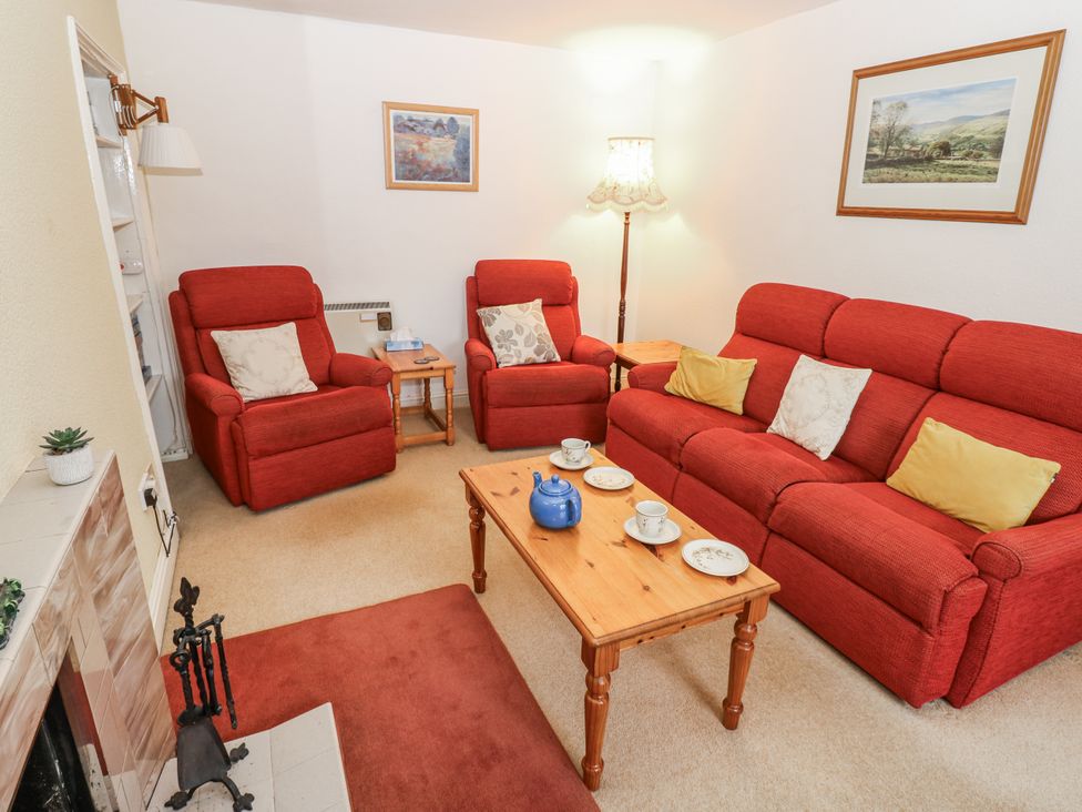 A living room with red furniture and a coffee table at Ivy Cottage in West Burton