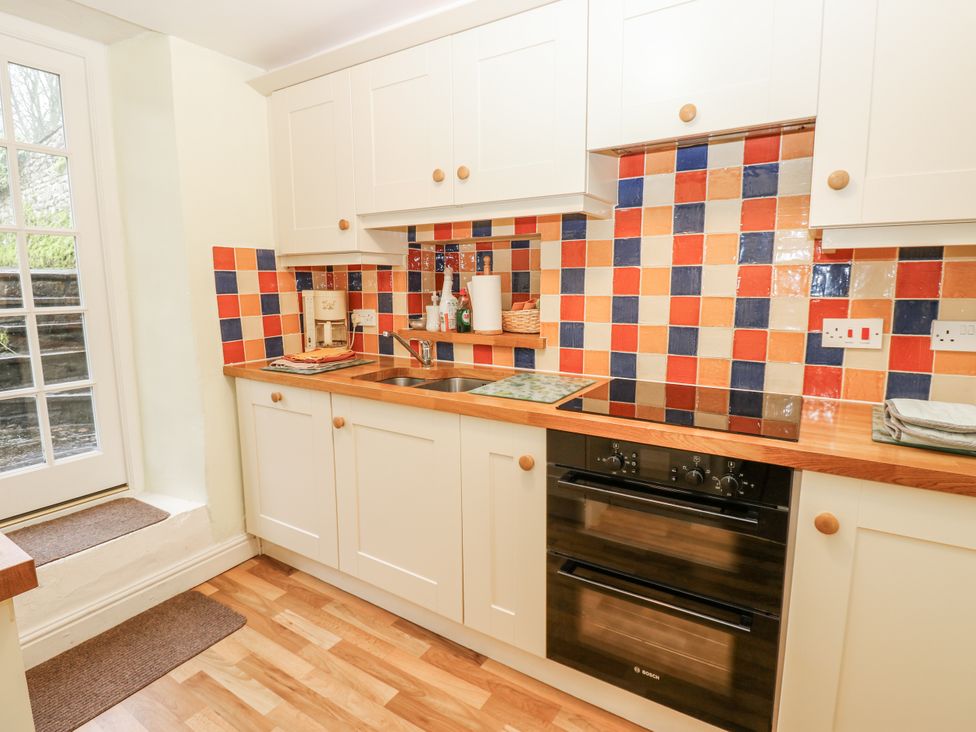 A kitchen with cabinets and a countertop at Ivy Cottage in West Burton