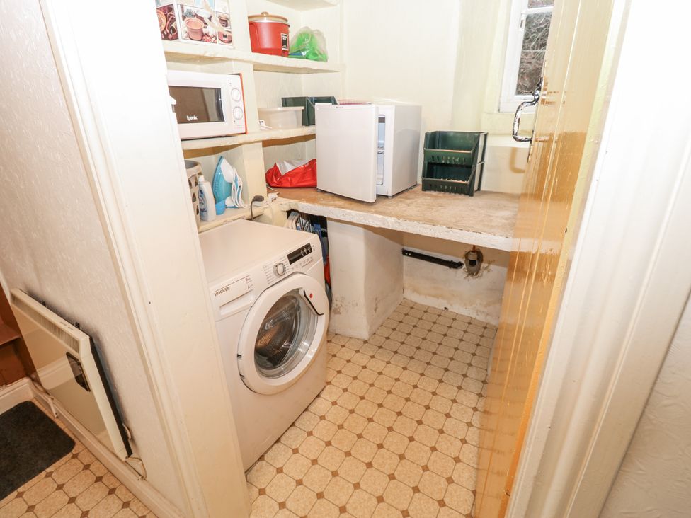 A laundry room with a washing machine and microwave at Ivy Cottage West Burton