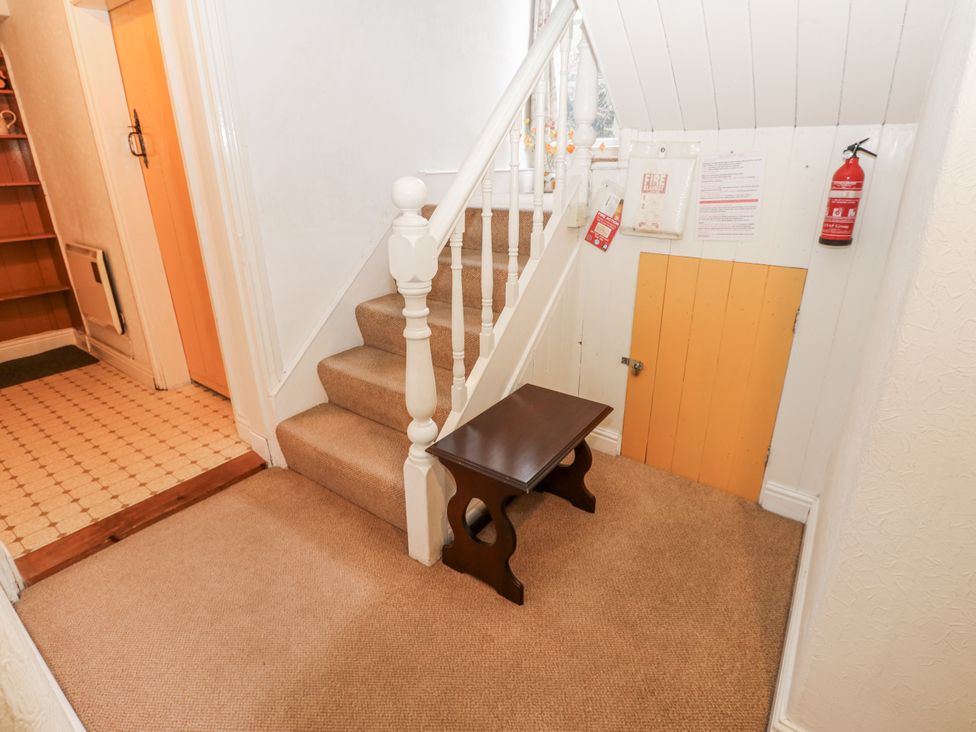 A hallway with a staircase and a small table at Ivy Cottage in West Burton
