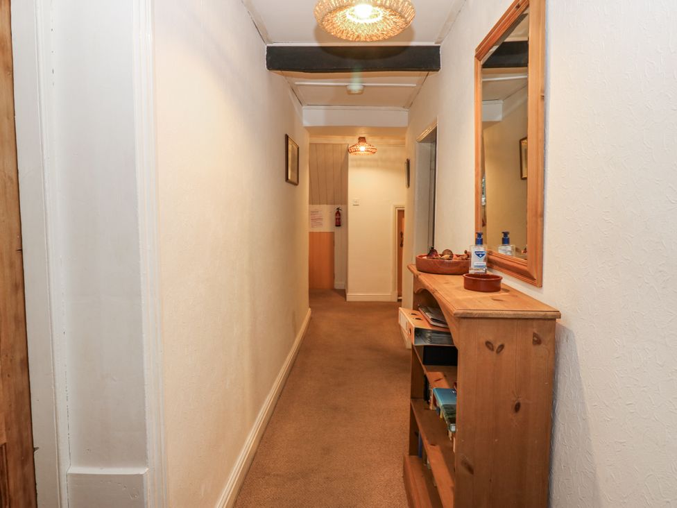 A hallway with a mirror and shelf at Ivy Cottage in West Burton
