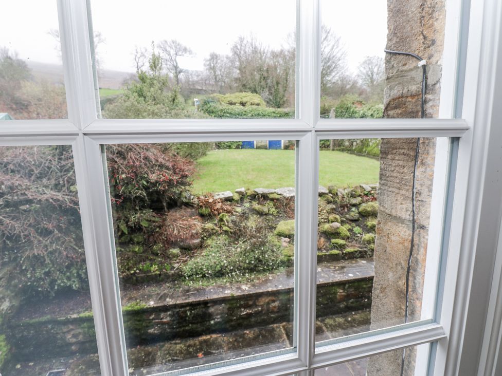 A view of a garden with grass and a stone wall at Ivy Cottage in West Burton
