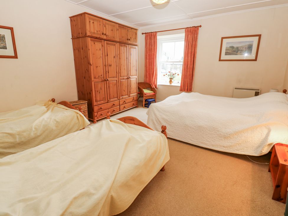 A bedroom with two beds and a wardrobe at Ivy Cottage in West Burton