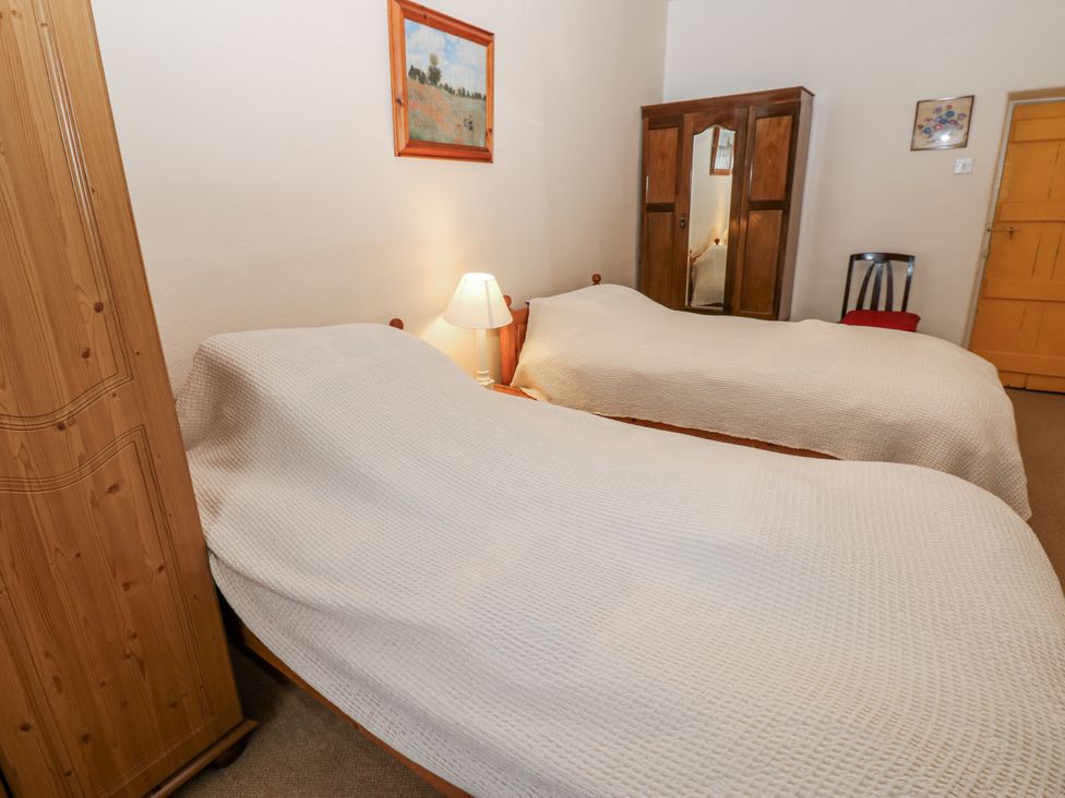 A bedroom with two beds and a wardrobe at Ivy Cottage in West Burton