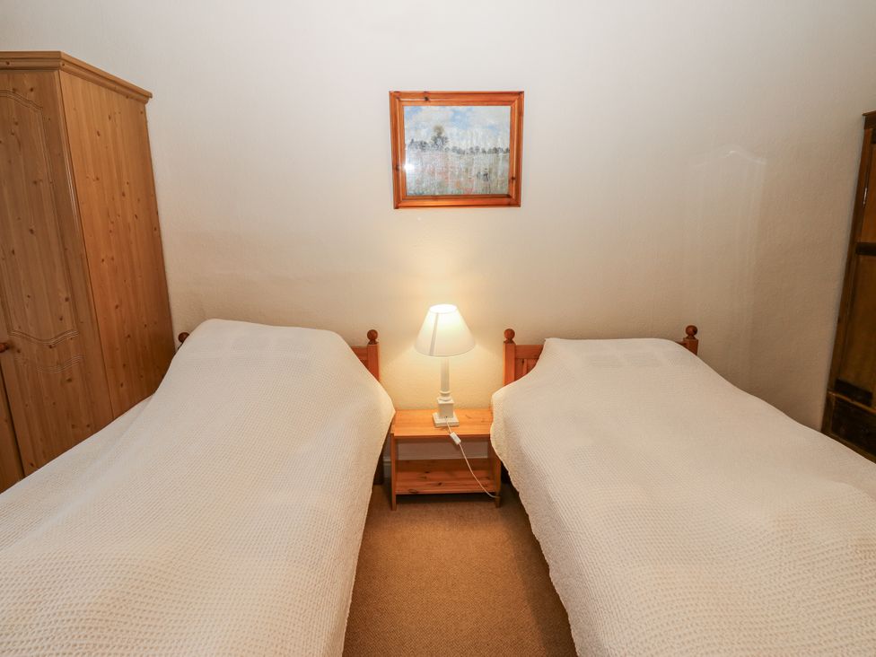A bedroom with two beds and a lamp at Ivy Cottage in West Burton