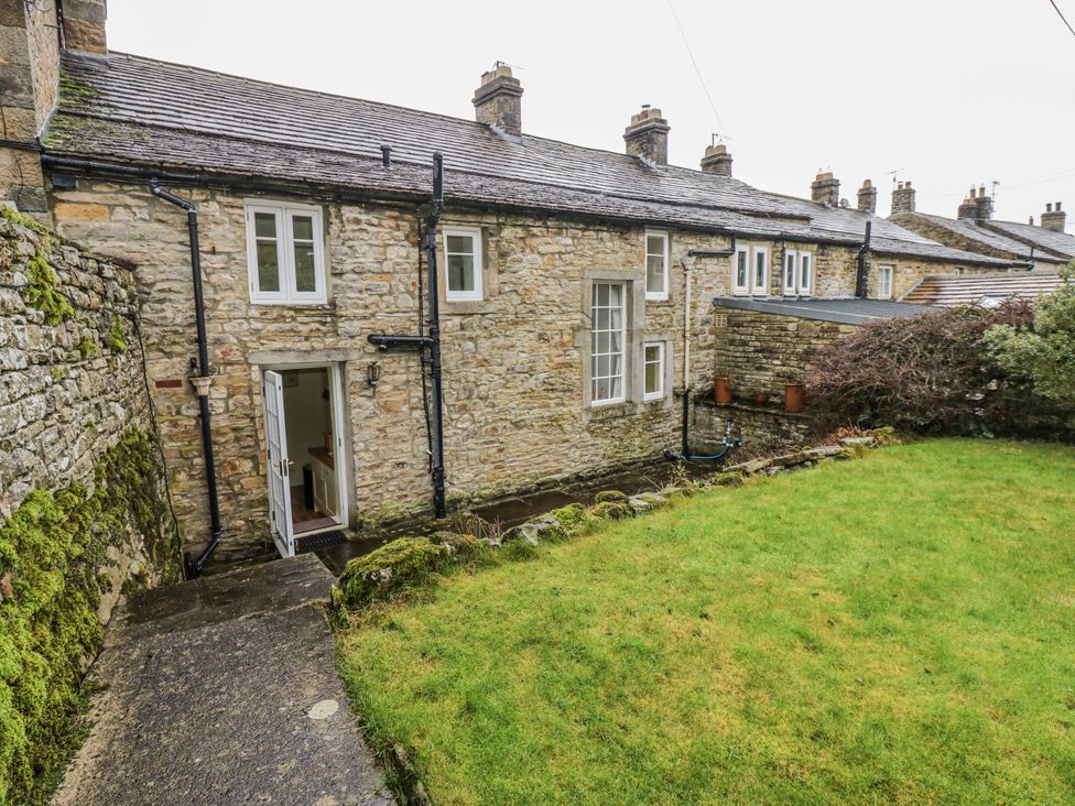 An outdoor area with a stone wall and grass at Ivy Cottage in West Burton