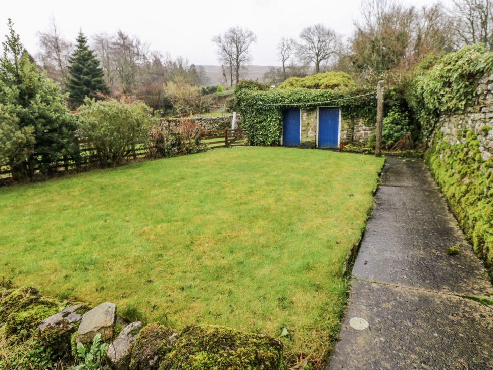 A garden with grass and a stone pathway at Ivy Cottage in West Burton