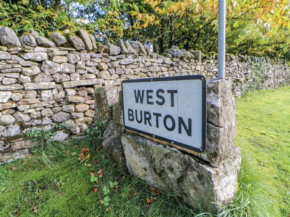A sign for West Burton next to a stone wall and grass at Ivy Cottage West Burton