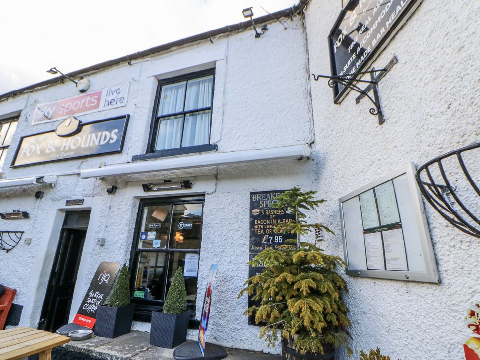 An outdoor area of a pub with a sign and menu at Fox & Hounds in West Burton