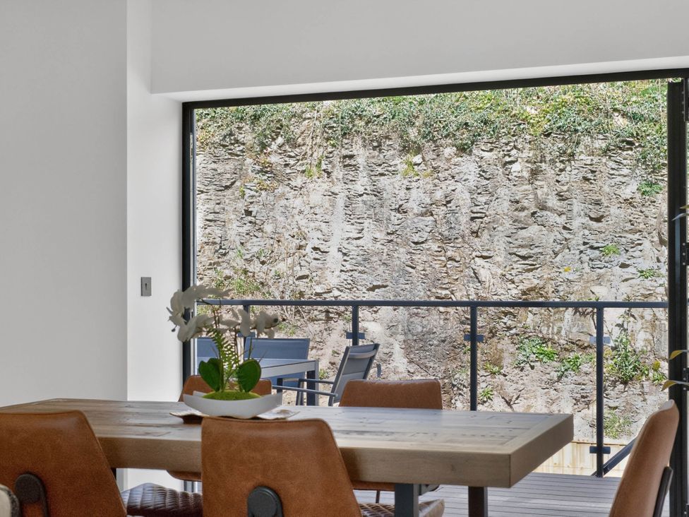 A dining room with a table and chairs overlooking a rock wall at Heddfan in Carmarthen