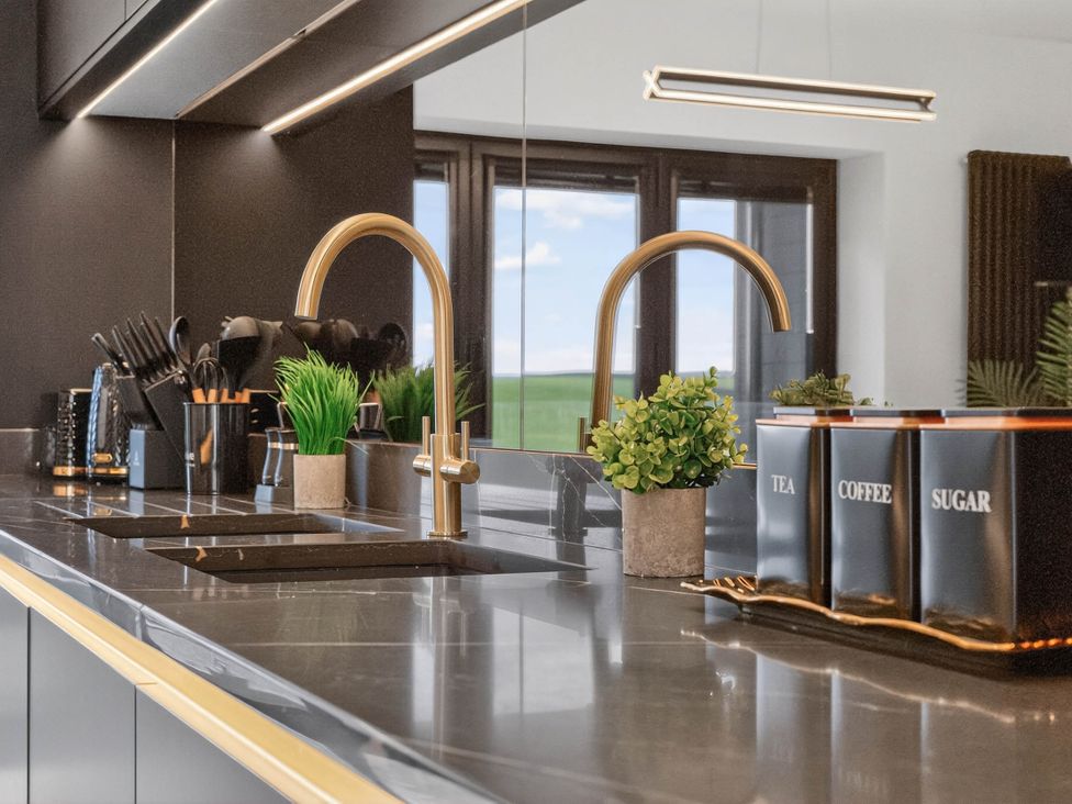 A kitchen with a sink faucet and storage containers at Heddfan in Carmarthen