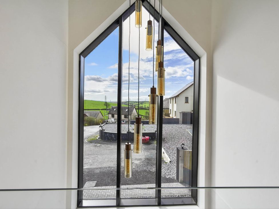A window with light fixtures showing an outdoor view at Heddfan in Carmarthen