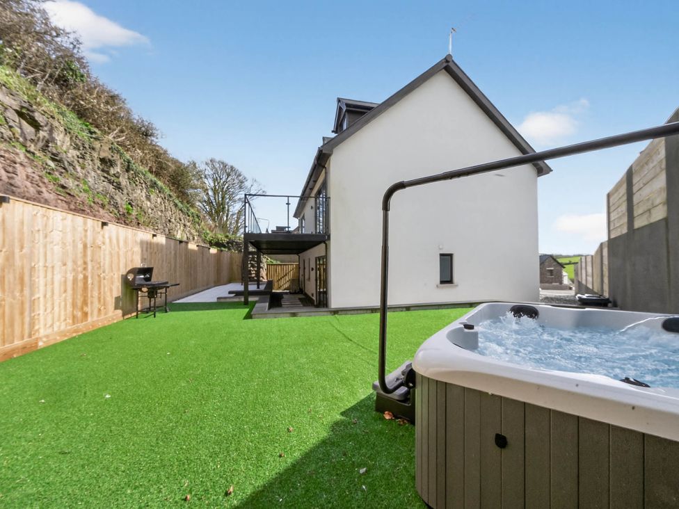 A garden with a hot tub and outdoor seating at Heddfan in Carmarthen