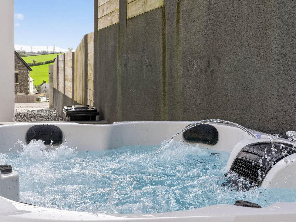 A hot tub with water and splashes near a fence at Heddfan in Carmarthen