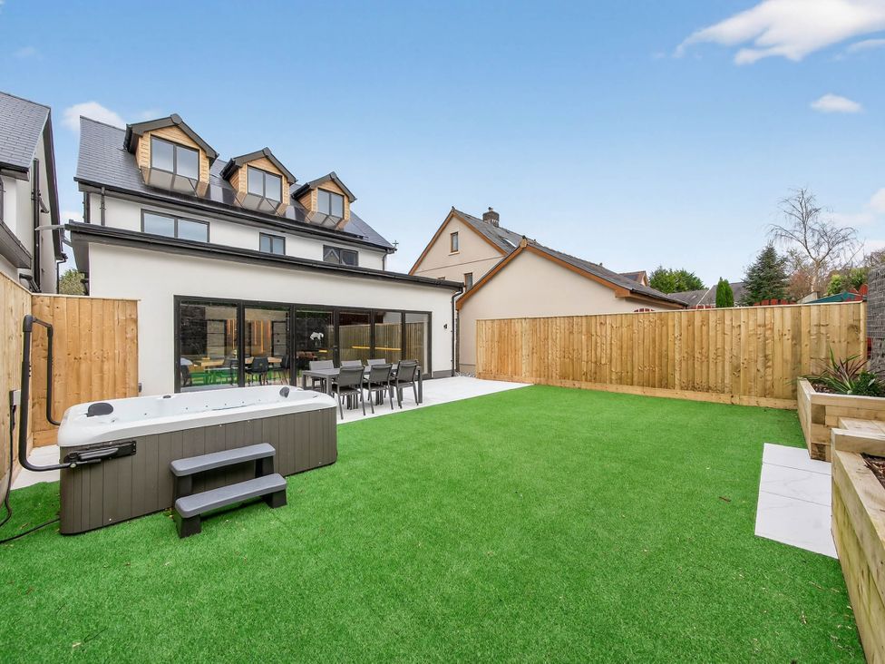 A garden with a hot tub and dining set at Ty Uchel in 