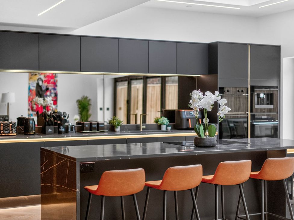 A kitchen with an island and stools at Ty Uchel