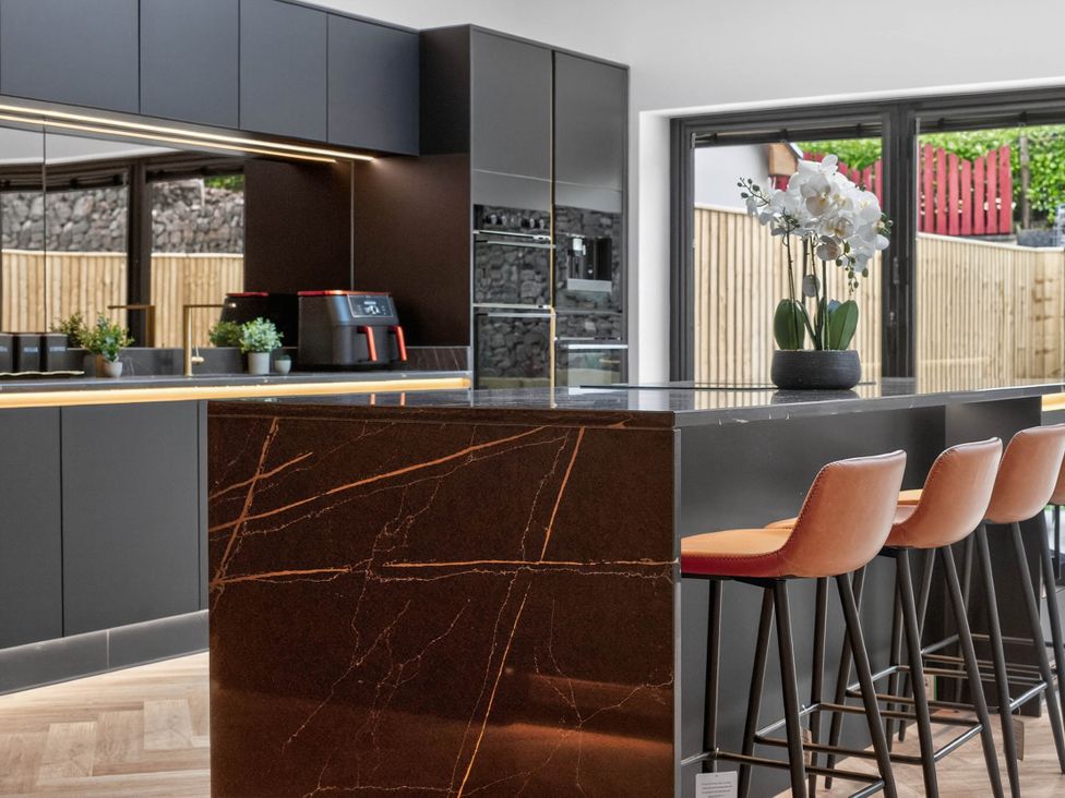 A kitchen with a dining area featuring a bar island and stools at Ty Uchel 