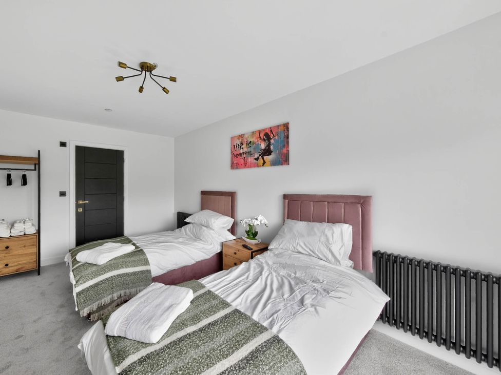 A bedroom with two beds and a nightstand at Ty Uchel