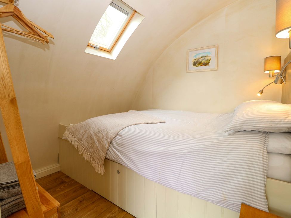 A bedroom with a bed and shelf at Grape Escape near Halesworth