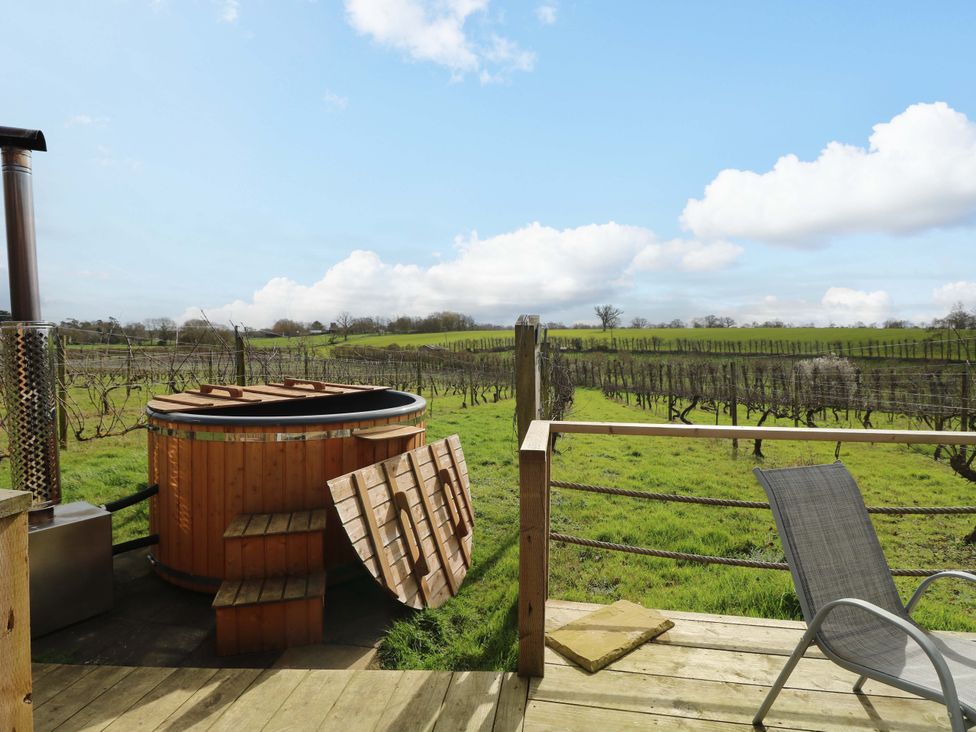 An outdoor area with a hot tub and a vineyard at Grape Escape near Halesworth