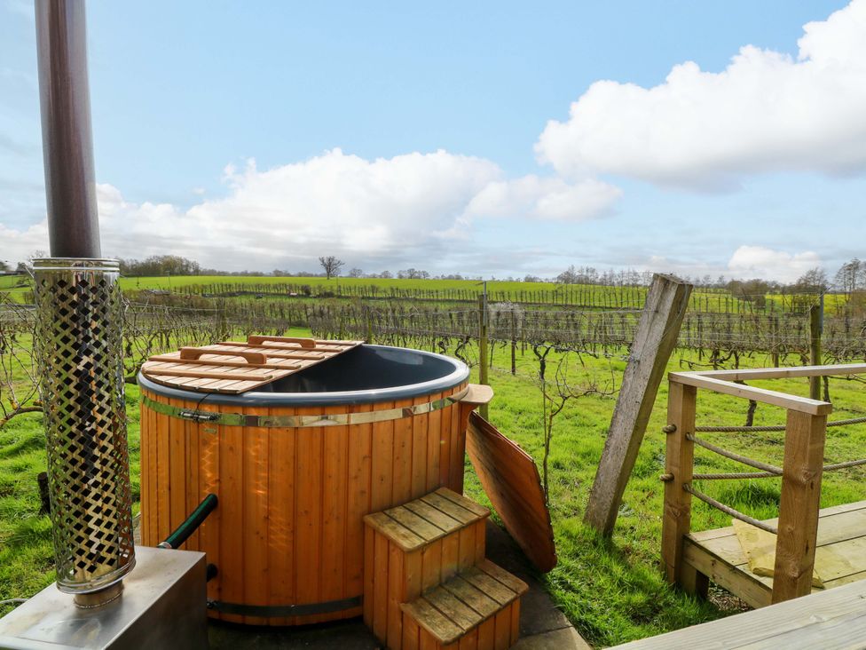 A hot tub with wooden steps and chimney near a vineyard at Grape Escape near Halesworth