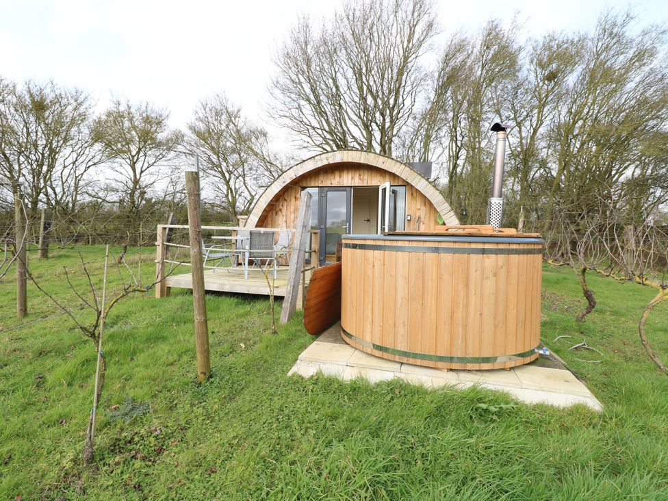 A wooden cabin with a hot tub in an outdoor setting at Grape Escape near Halesworth