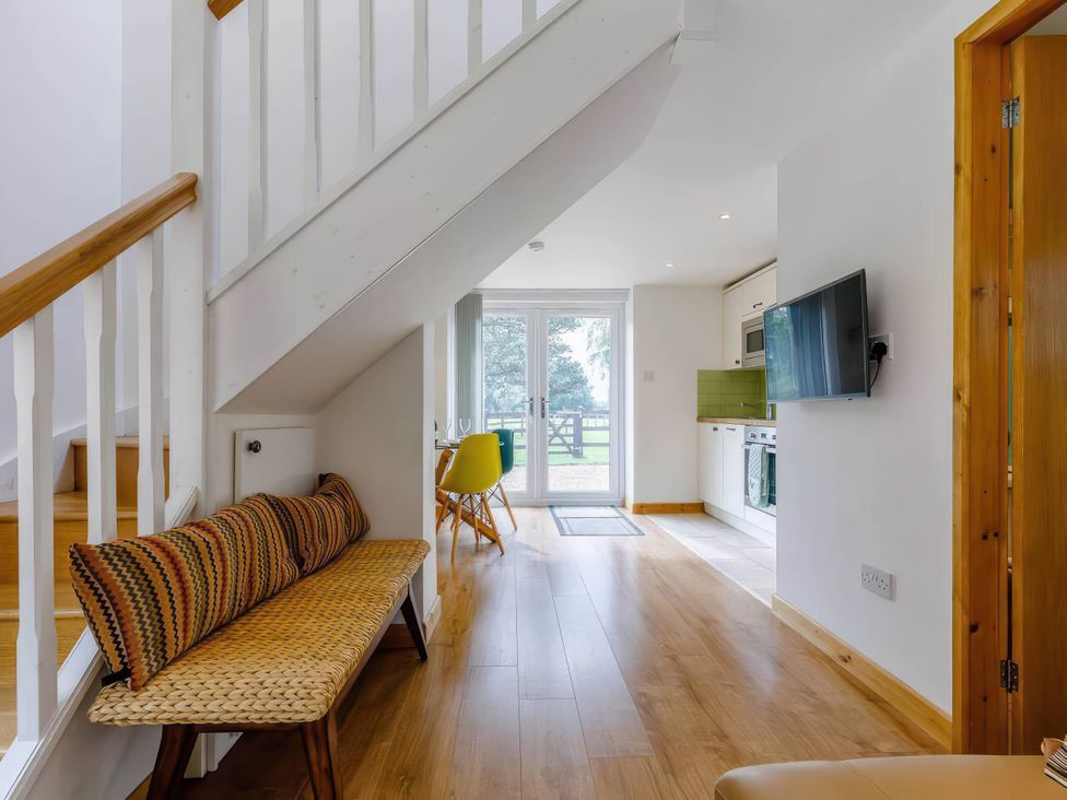 A living room with a bench and staircase at Acorn Cottage in Knutsford