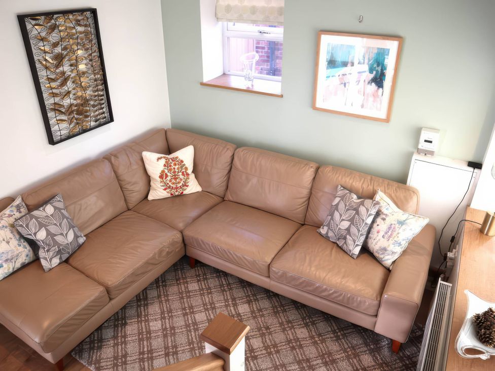 A living room with a sectional sofa and wall art at Acorn Cottage in Knutsford