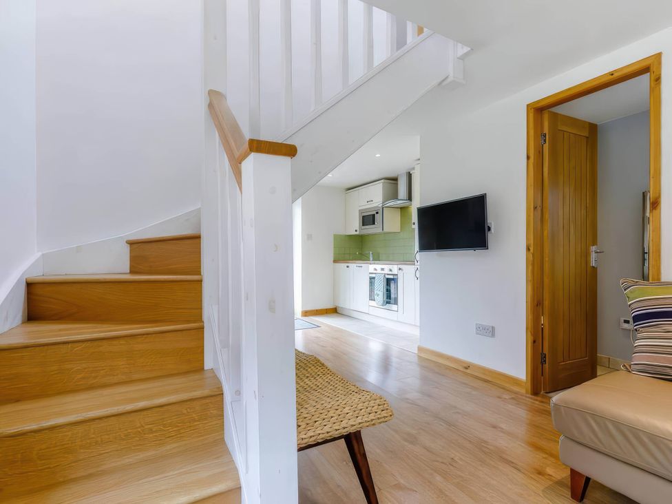 A hallway with a staircase and view of the kitchen at Acorn Cottage in Knutsford