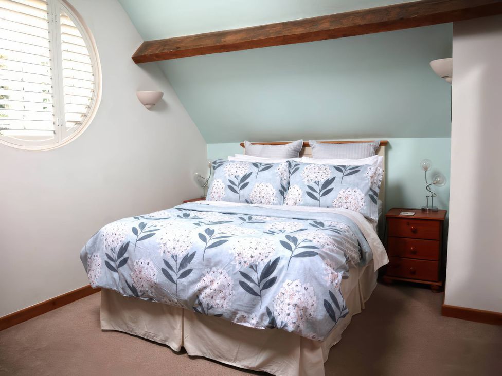 A bedroom with a bed and nightstand at Acorn Cottage in Knutsford